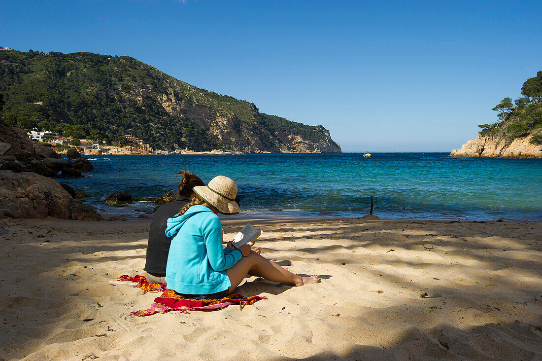 Two women reading on the beach, Aiguablava, near Begur, Costa Brava, Spain