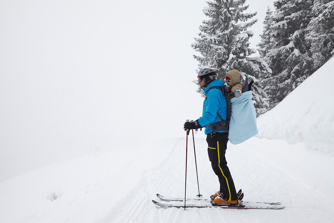 Skier carrying son on back, Lenggries, Brauneck, Bavaria, Germany