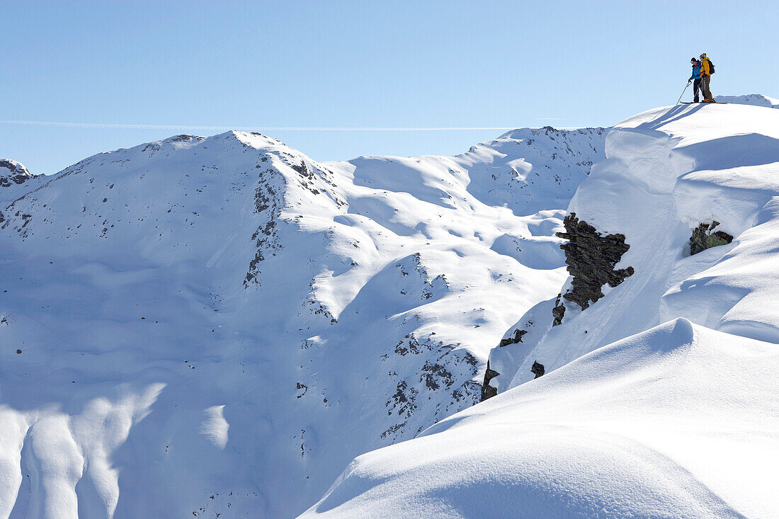 Two skiers standing on cornice, Davos, Grisons, Switzerland