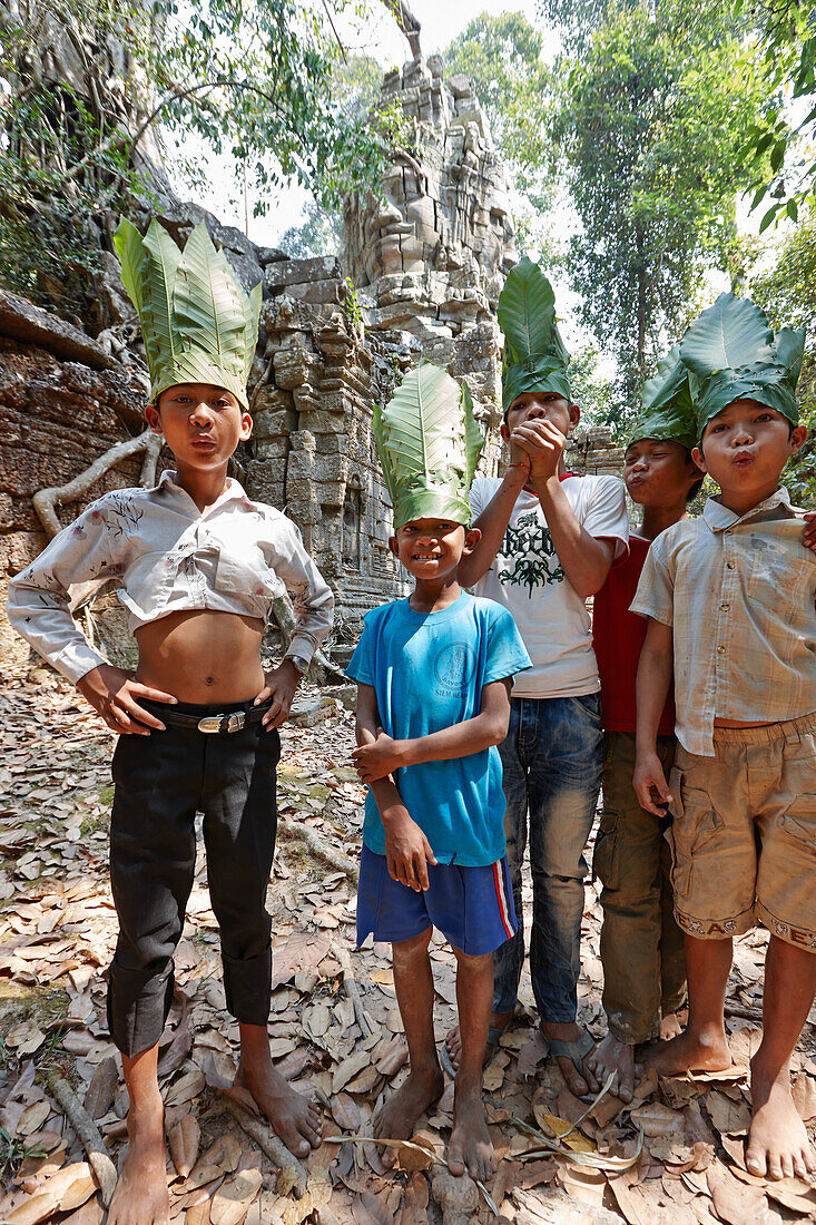 Jungen mit Hüten aus Bananenblättern, Tempeltor im Wald, Ta Prohm Tempelruine, Angkor, Siem Reap, Kambodscha