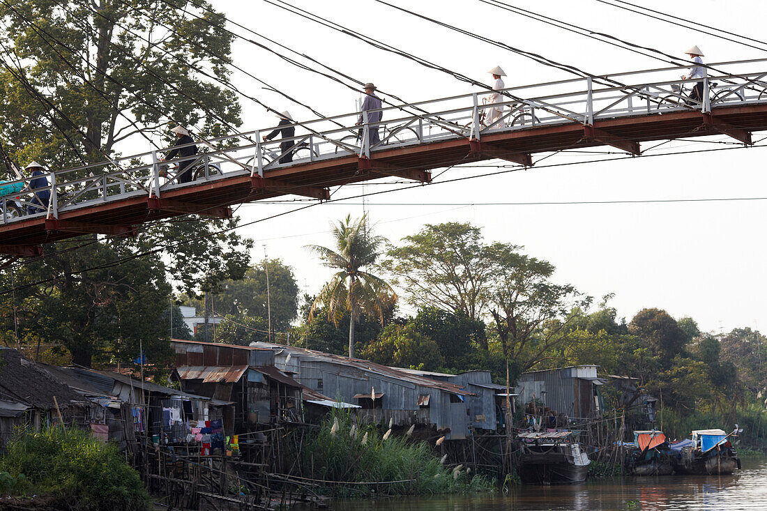Stilted houses and suspension bridge over Mekong canal, Long Xuyen, An Giang Province, Vietnam
