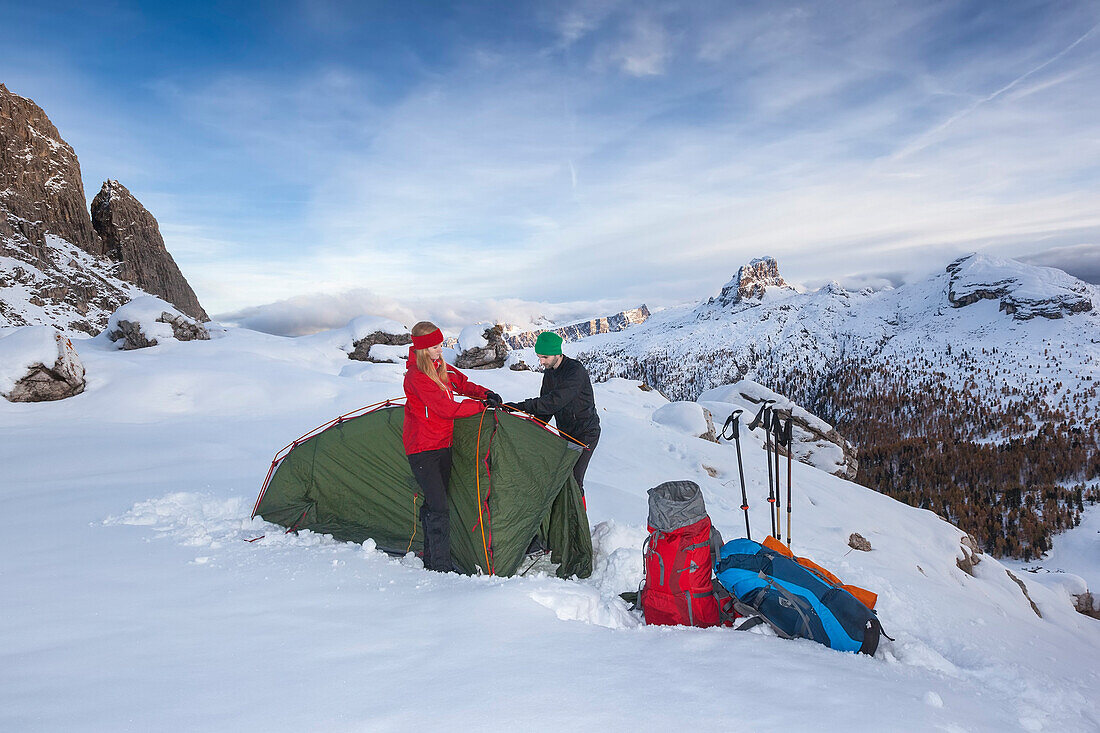 Junges Paar baut Zelt im Schnee auf, Dolomiten, Belluno, Venetien, Italien