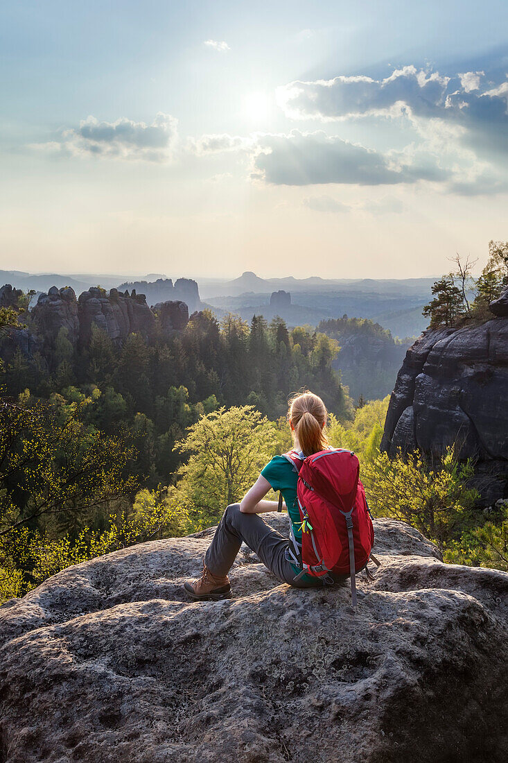Young woman sitting on a rock while looking at view, Saxon Switzerland National Park, Saxony, Germany