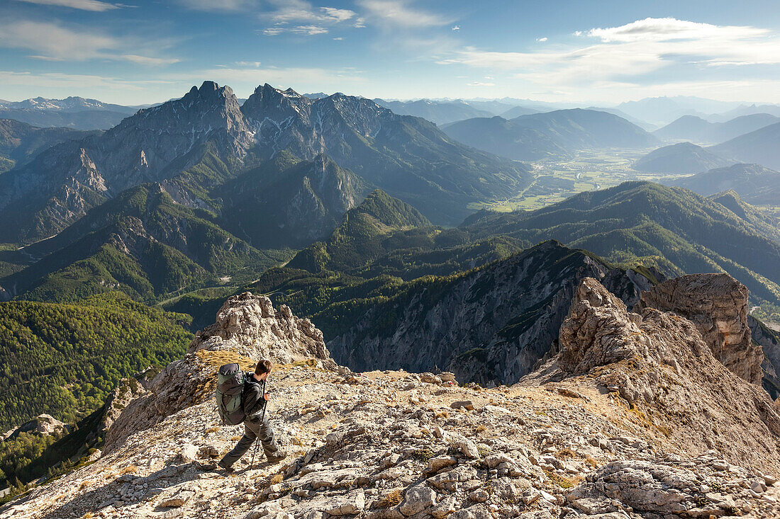 Junger Mann mit Rucksack wandert auf einem Bergpfad am Großen Buchstein, Nationalpark Gesäuse, Hochtor und Admonter Reichensteingruppe im Hintergrund, Ennstaler Alpen, Steiermark, Österreich
