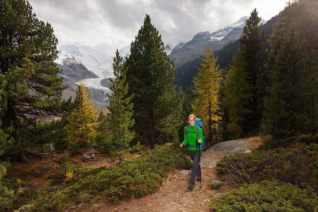 Young woman with backpack hiking in Morteratsch Valley, Bernina Range in background, Engadin, Canton of Grisons, Switzerland