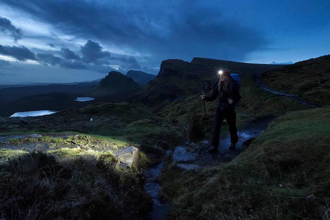Young woman with headlamp hiking in twilight, Quiraing, Trotternish peninsula, Isle of Skye, Scotland, United Kingdom