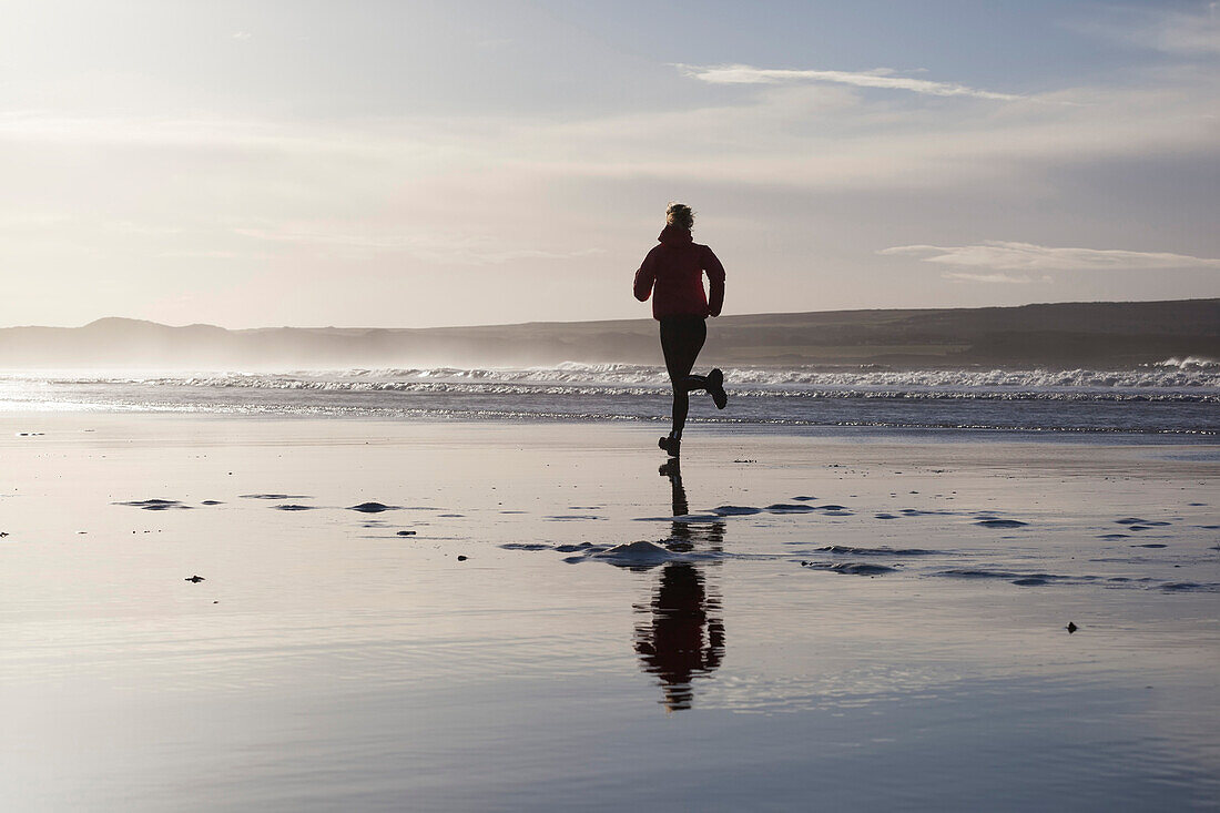 Young woman jogging at beach, Dunnet Bay, Caithness, Scotland, United Kingdom