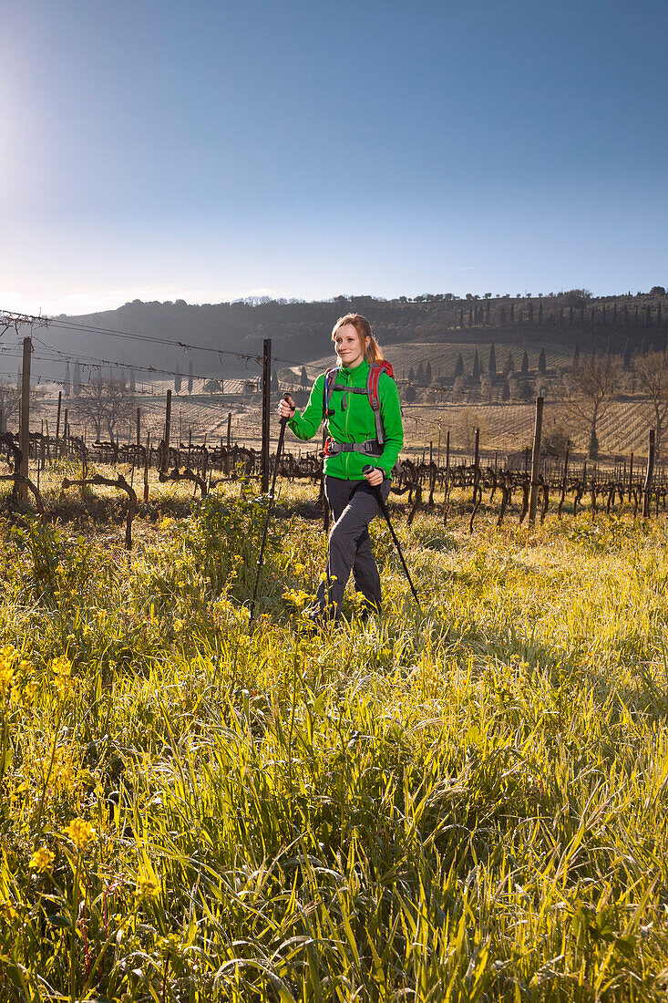 Young woman hiking across a vineyard, Val d Orcia, Tuscany, Italy