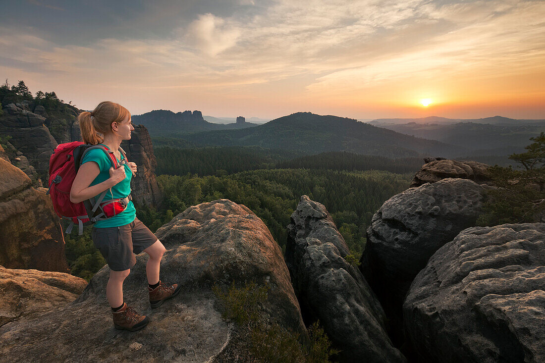 Junge Frau betachtet Sonnenuntergang, Nationalpark Sächsische Schweiz, Sachsen, Deutschland