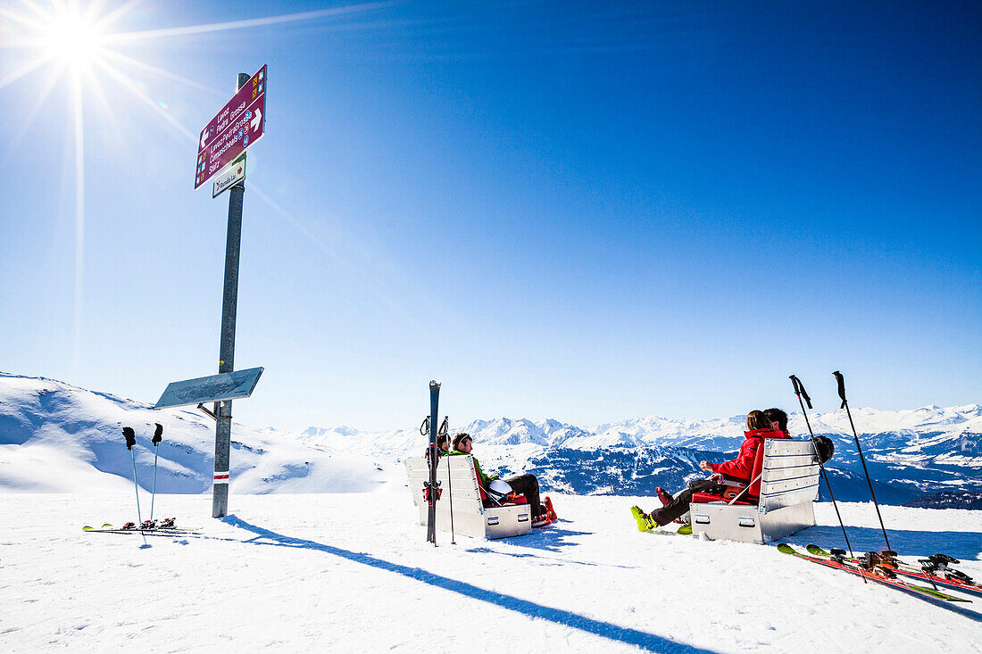 Junge Frauen und Männer sonnen auf Sofas (Sonennboxen) im Skigebiet, Bergstation Lavoz Bahn, Skigebiet Lenzerheide, Graubünden, Schweiz