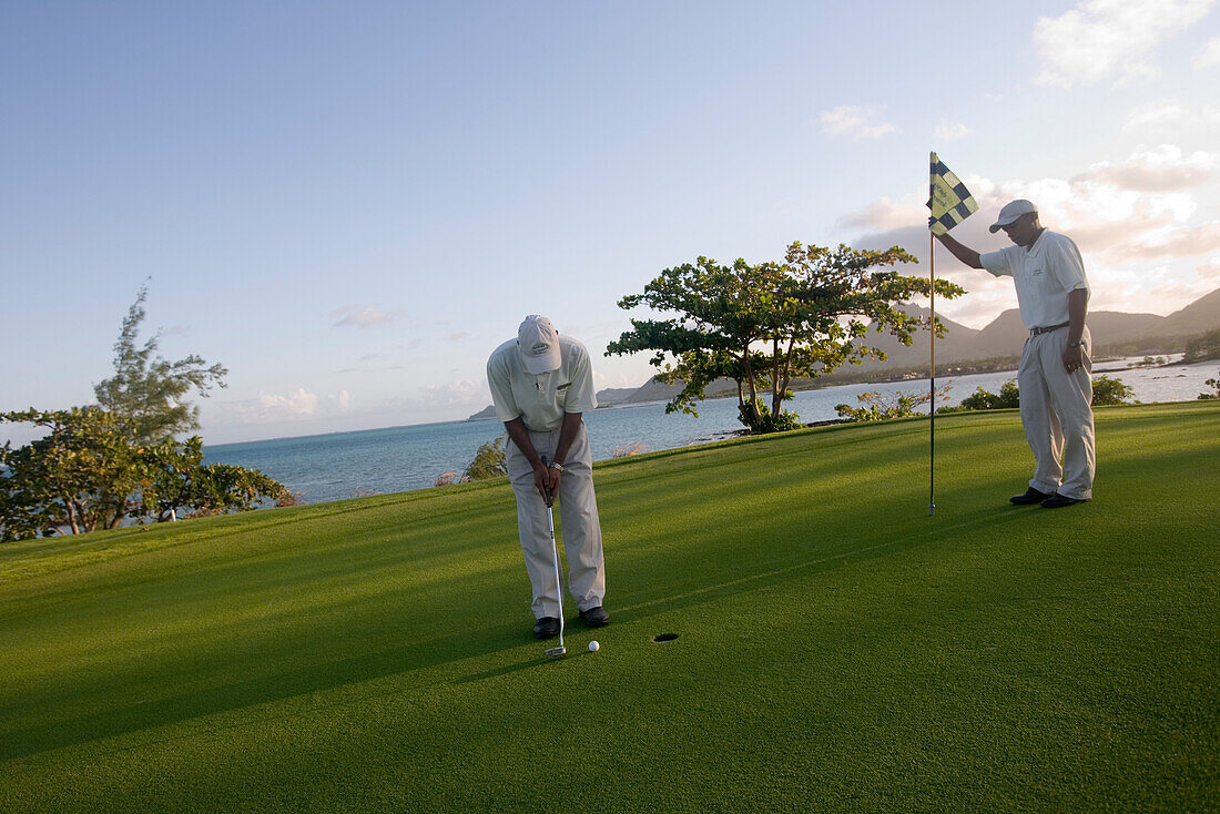 Golfer puting on the Green of Hole 11: Round the Bend at Le Touessrok Golf Course, Ile aux Cerfs Island, near Trou d'Eau Douce, Flacq District, Mauritius