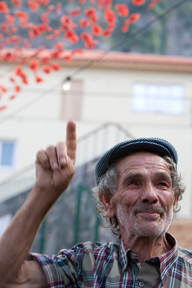 Bitte ein Bit! Fröhlicher alter Mann hebt Zeigefinger während Fest zur Ehre von Schutzheiligen, Ponta Delgada, Madeira, Portugal, Europa