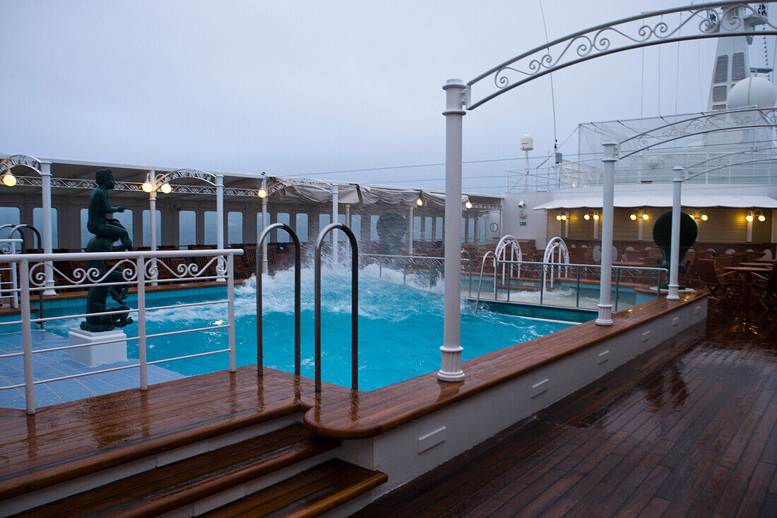 Wasser schwappt über den Beckenrand vom Pool an Bord von Kreuzfahrtschiff MS Deutschland (Reederei Peter Deilmann) während stürmischer See im Südatlantik, nahe Falkland-Inseln