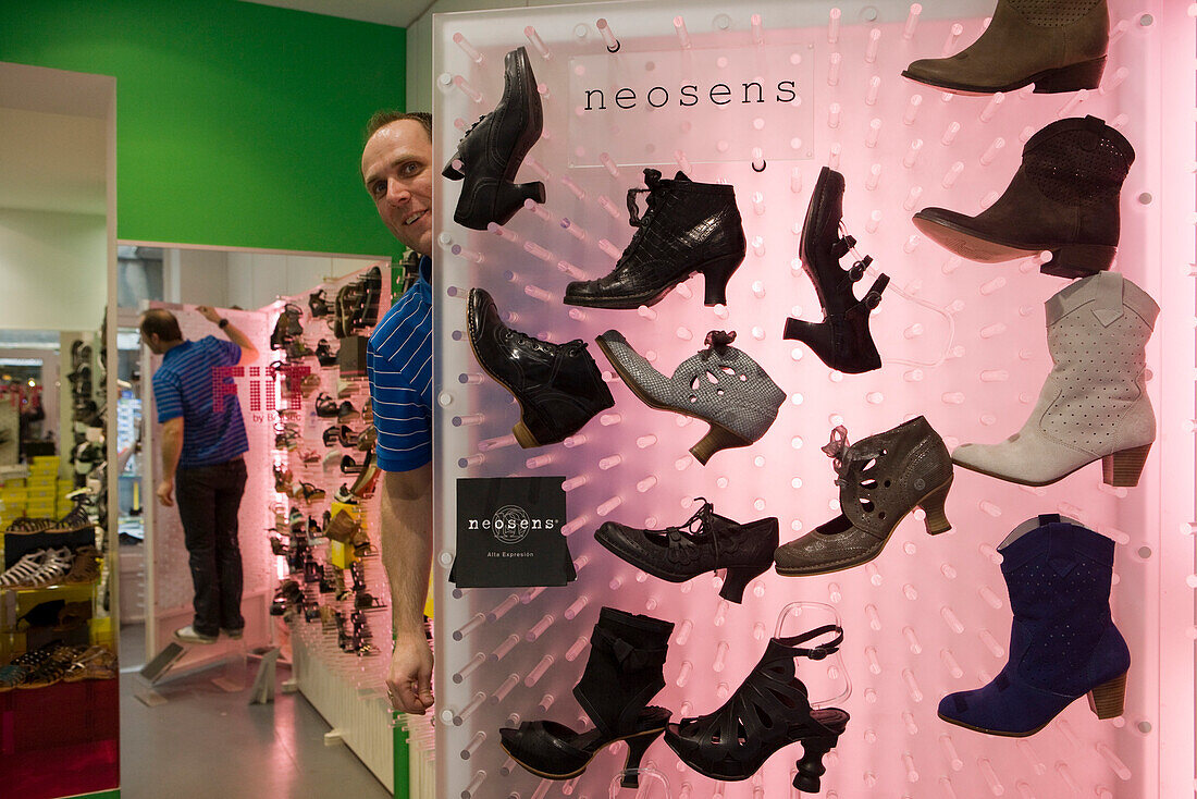 Man peaking from behind a shoe store display, St. Malo, Brittany, France