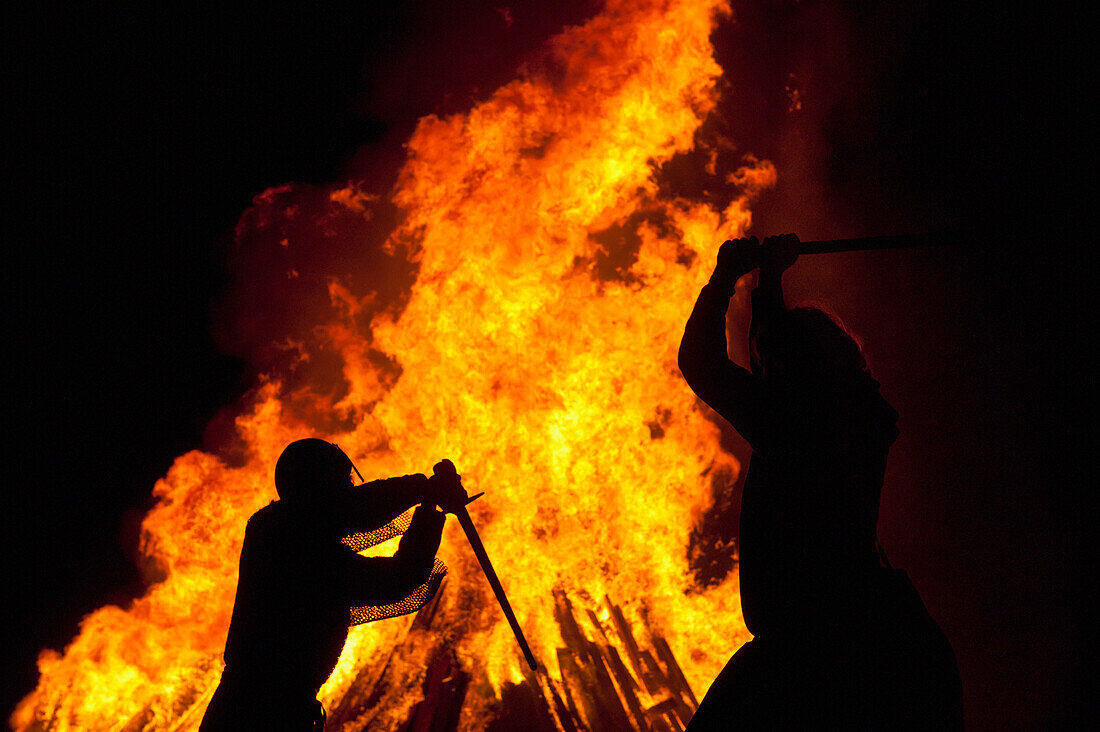 Silhouette Of Men Dressed As Norman Soldiers In Front Of Large Bonfire On Beach, Hastings Bonfire Night, East Sussex, Uk
