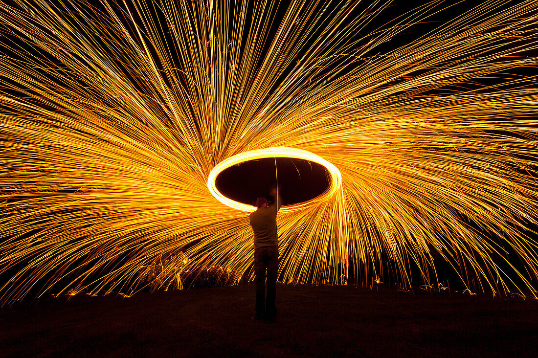 Man Spinning Ball Of Burning Steel Wool At Night, Petersfield, Hampshire, Uk
