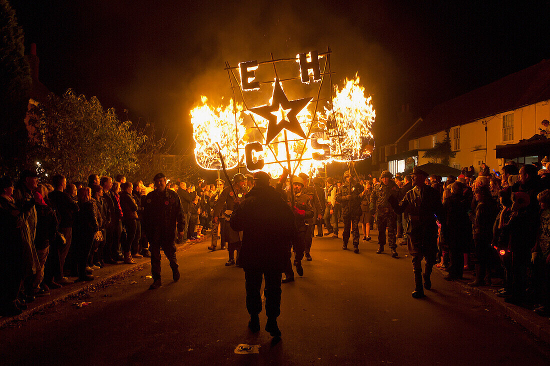 People From East Hoathly & Halland Carnival Society Carrying Banner And Burning Poppies Through East Hoathly On Bonfire Night, East Sussex, Uk