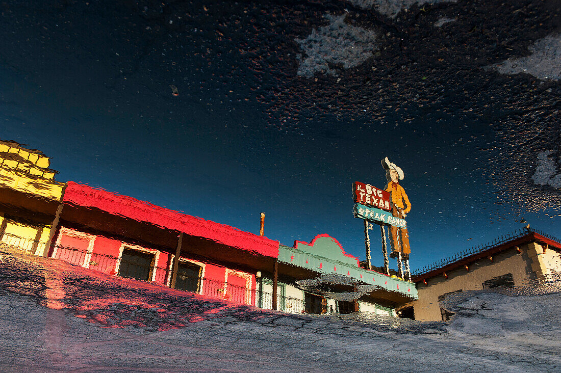Puddle Reflecting The Motel Rooms And Roadsign Outside The Big Texan Steak Ranch Restaurant, Amarillo, Texas, Usa
