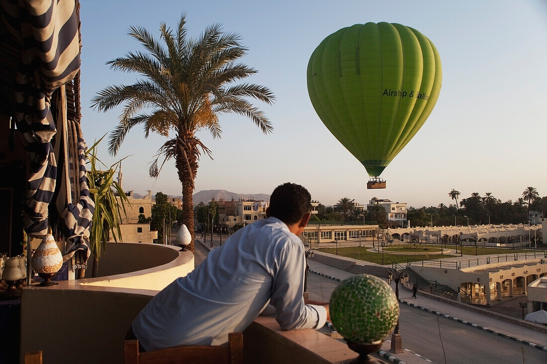 Hotel worker watching hot air balloon from hotel balcony, west bank luxor upper egypt