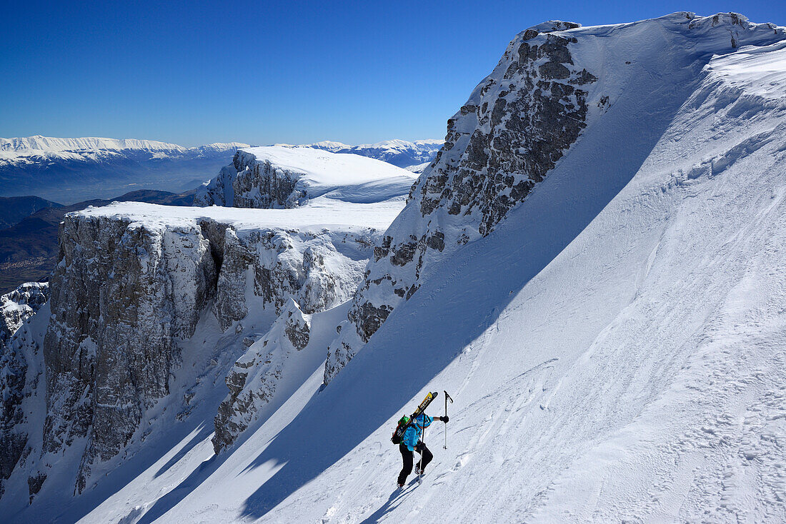 Skitourengeherin steigt durch Schneekar am Monte Sirente auf, Majellagruppe im Hintergrund, Valle Lupara, Abruzzen, Italien