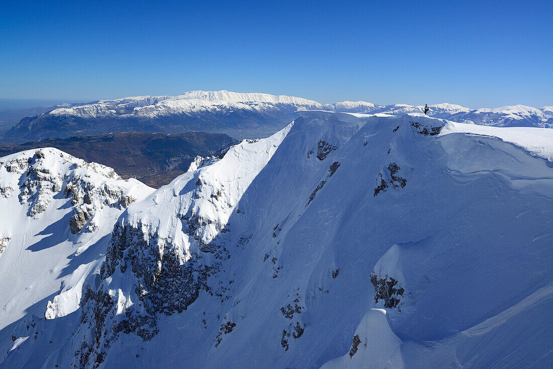Skitourengeherin steigt zum Monte Sirente auf, Majellagruppe im Hintergrund, Valle Lupara, Abruzzen, Italien