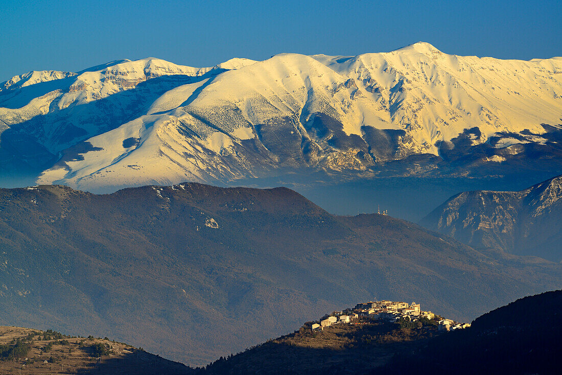Ortschaft steht vor verschneiter Majellagruppe mit Monte Pesco Falcone und Monte Amaro, Abruzzen, Apenninen, l 'Aquila, Italien