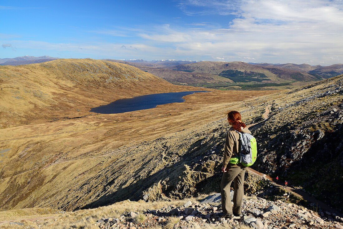 Frau beim Wandern blickt auf See Half Way Loch, Ben Nevis, Highlands, Schottland, Großbritannien