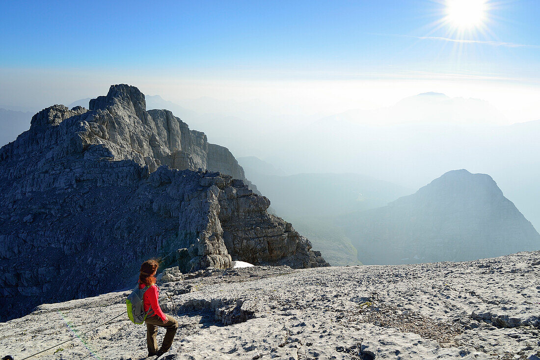 Frau auf Felsplatte betrachtet Aussicht, Hocheck im Hintergrund, Watzmann, Berchtesgadener Alpen, Nationalpark Berchtesgaden, Berchtesgaden, Oberbayern, Bayern, Deutschland