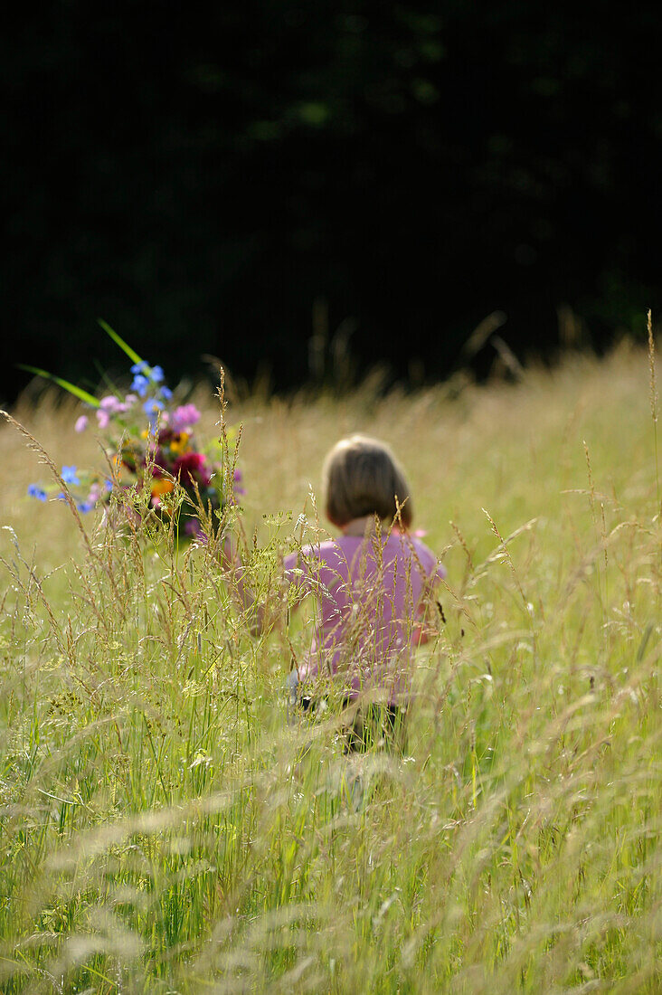 Child, young girl, holding a bunch of flowers in high gras in summer, Germany