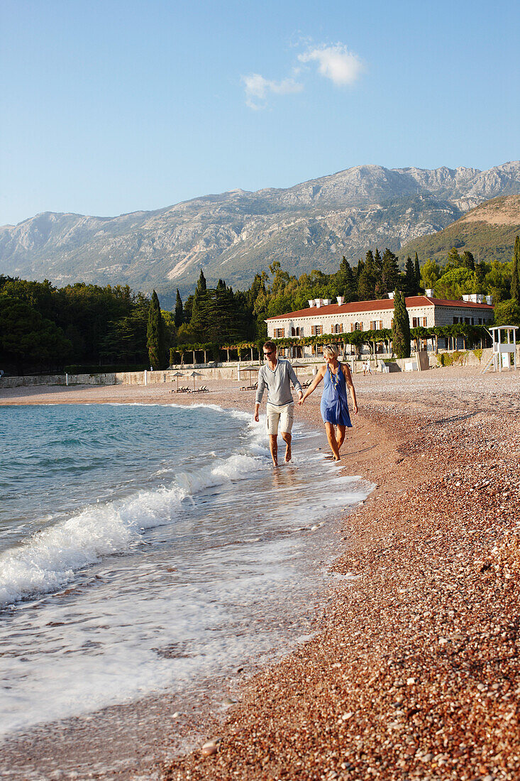 Paar am Strand, Villa Milocer in background, Aman Sveti Stefan, Sveti Stefan, Budva, Montenegro