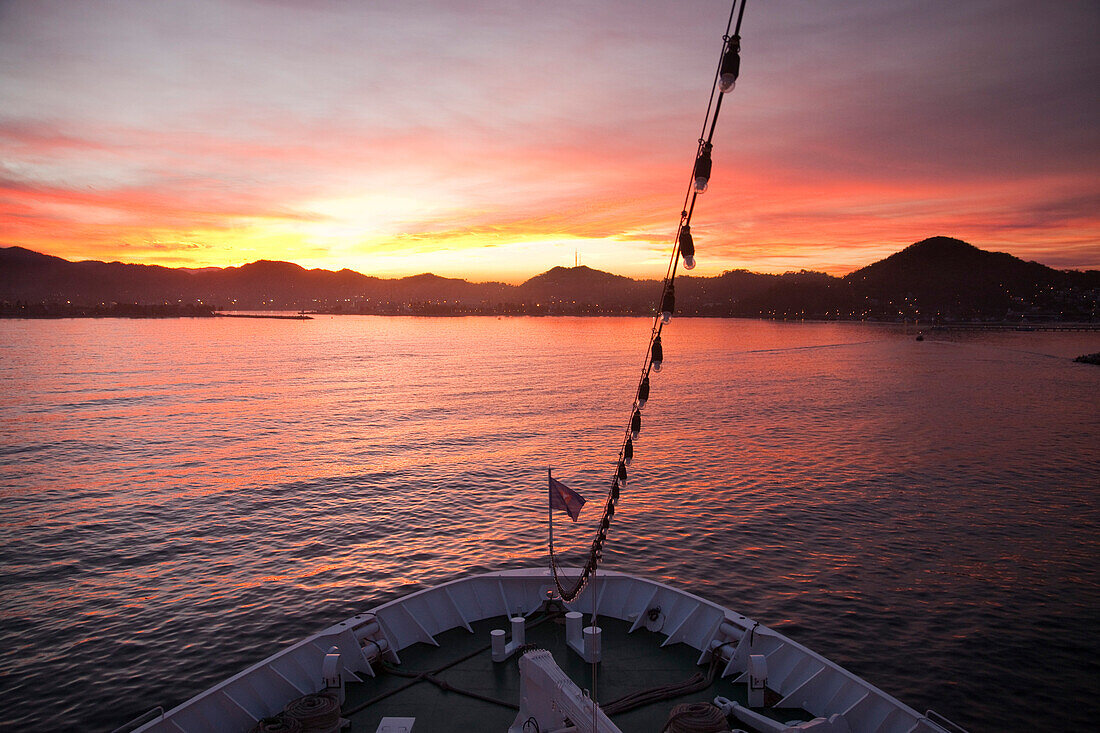 Bug von Kreuzfahrtschiff MS Deutschland (Reederei Peter Deilmann) und Küste bei Sonnenaufgang, Manzanillo, Colima, Mexiko, Mittelamerika