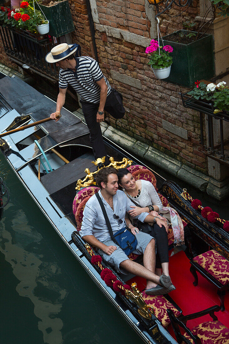 Glückliches Paar genießt eine Gondelfahrt auf einem Kanal, Venedig, Venetien, Italien, Europa