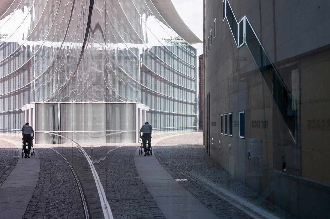 Reflection of man with walker in the window of the museum of modern art, Neues Museum, Nuremberg, Franconia, Bavaria, Germany