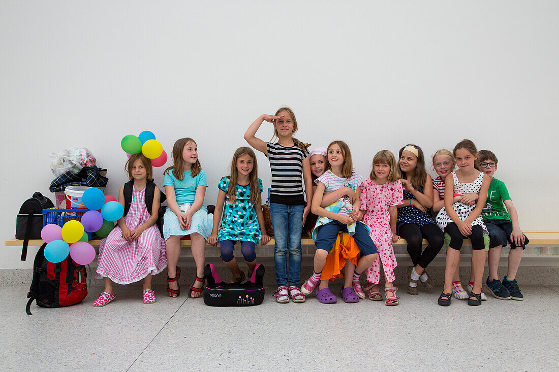 Children from a birthday party sitting on a bench at the  museum of cultural history, Germanisches Nationalmuseum, Nuremberg, Franconia, Bavaria, Germany