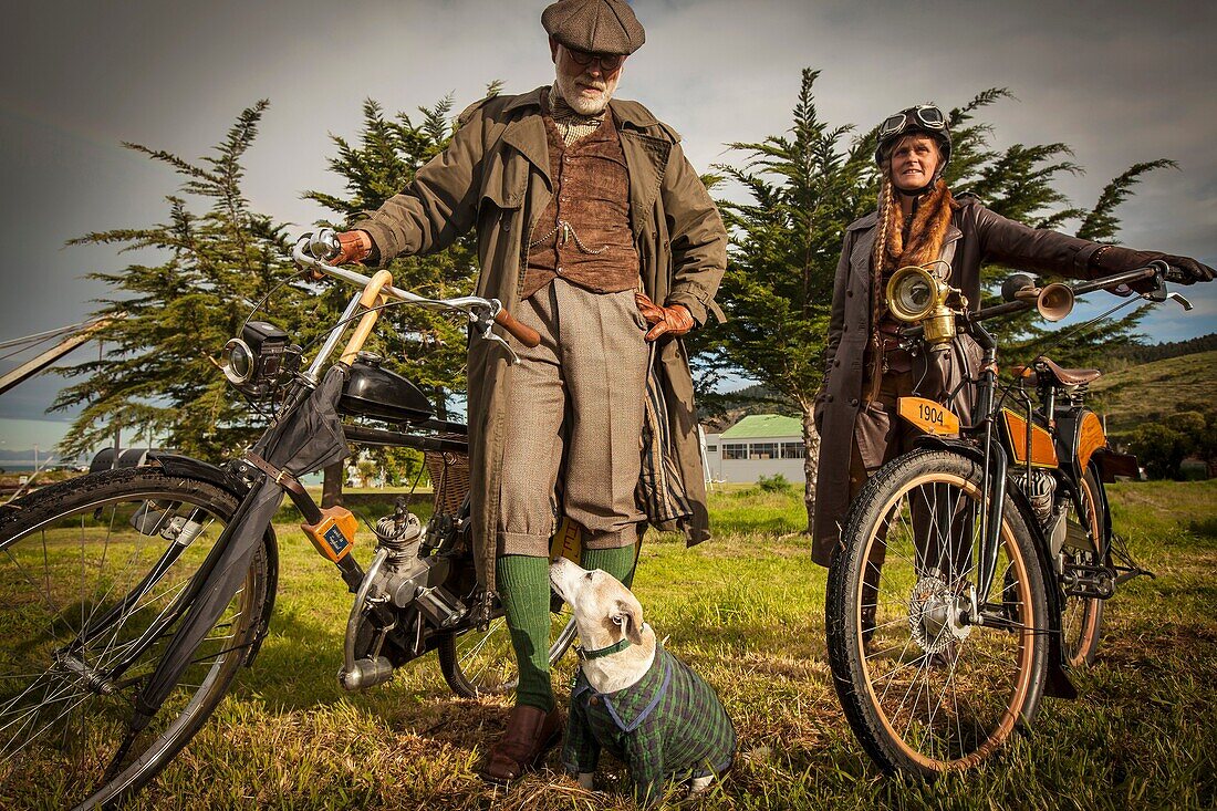 Lady and gentleman in Victorian costume with antique bicycles with small engines, Victorian festival, historic precinct, Oamaru, Otago