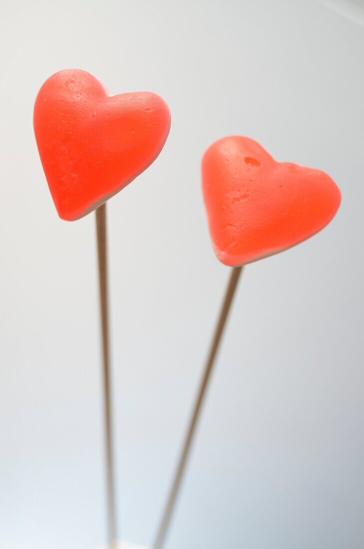 Two red hearts over wooden poles, gray background.