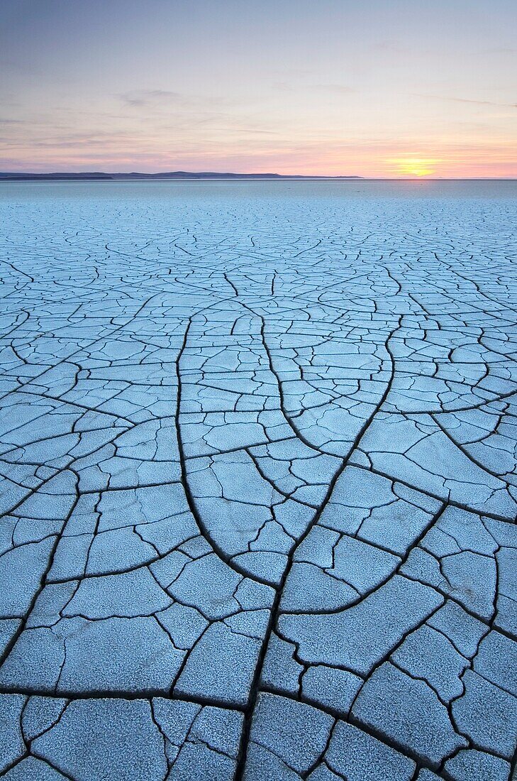 Setting sun on patterns of cracked mud on dry lakebed of Harney Lake, Malheur National Wildlife Refuge, Oregon