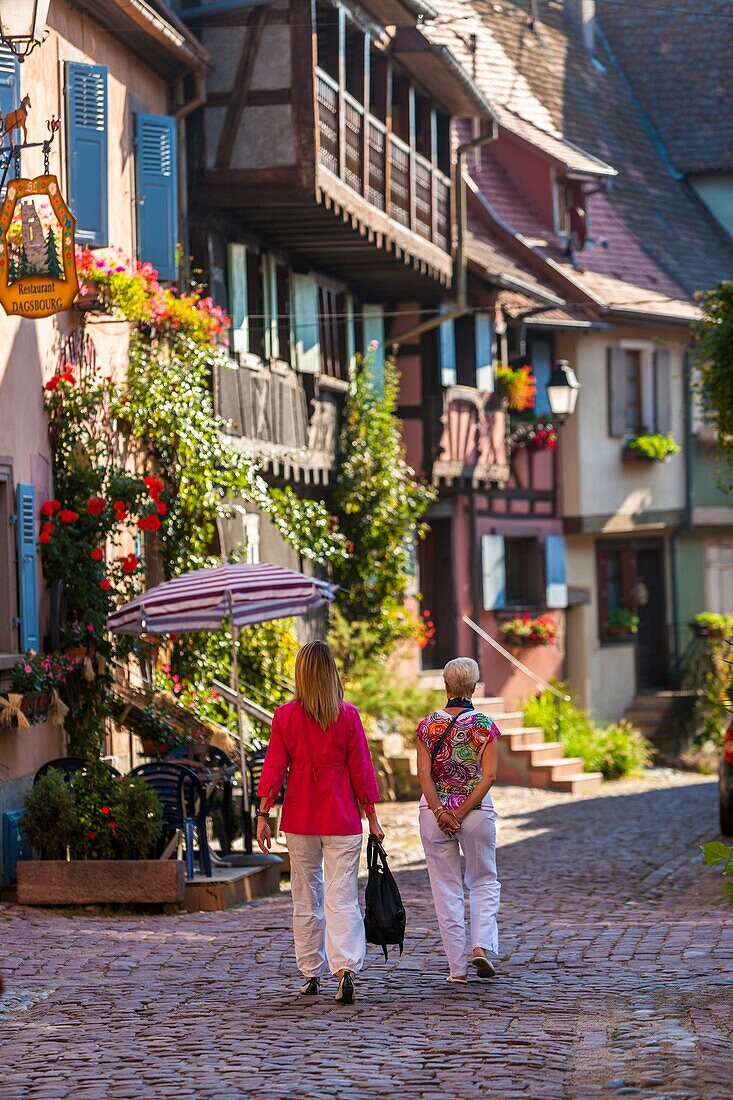 Two women strolling through the picturesque village of Eguisheim, Alsace, France, Europe