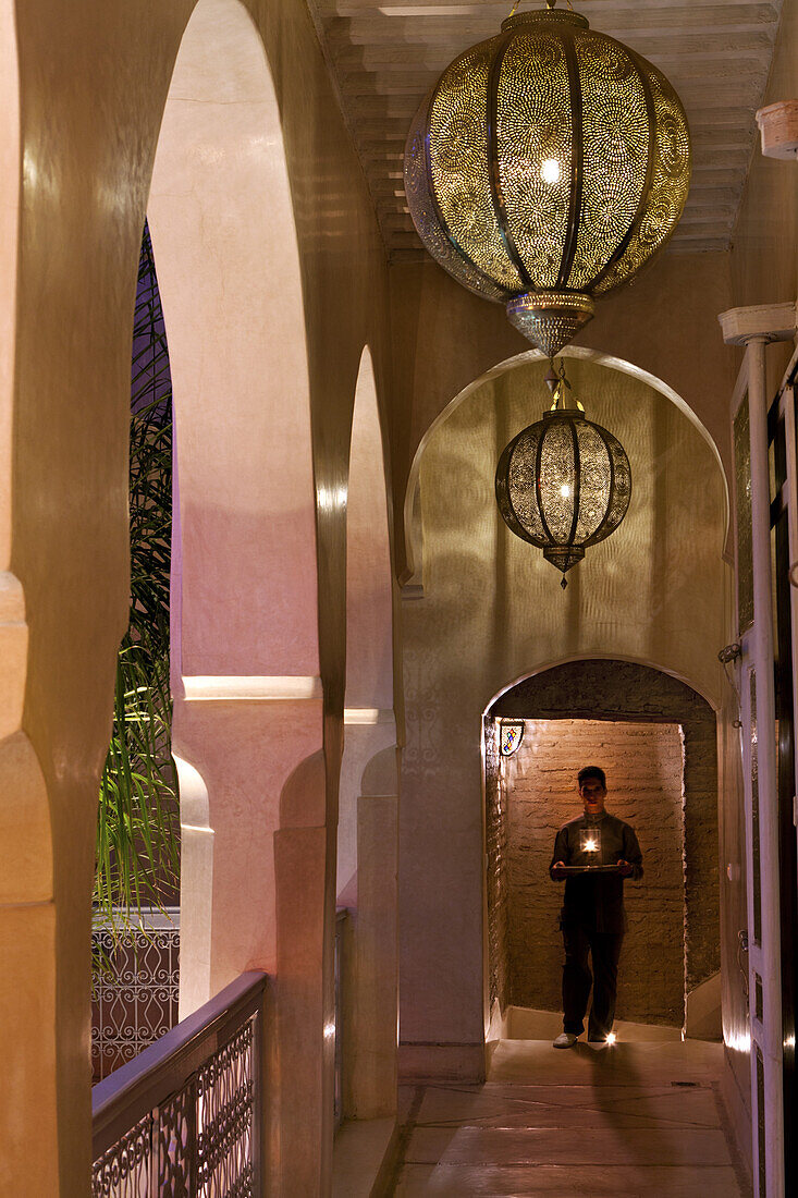 Young man walking with moroccan tea and a candle, Riad Anayela, Marrakech, Morocco