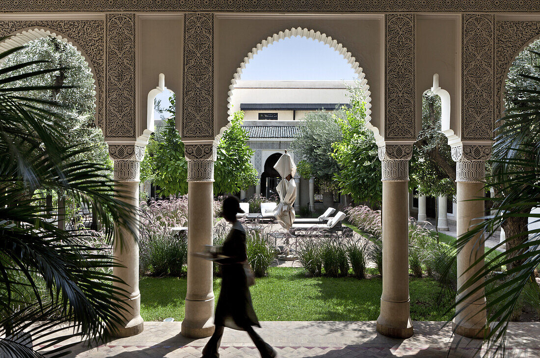 Woman walking through the arched passageway, Villa des Orangers, Marrakech, Morocco