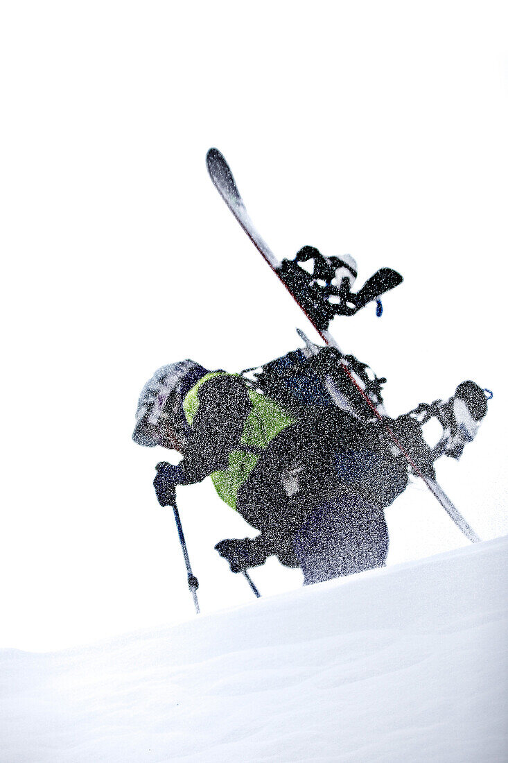 Junger Snowboarder steigt durch den Schnee in den Bergen bei Schneefall, Pitztal, Tirol, Österreich