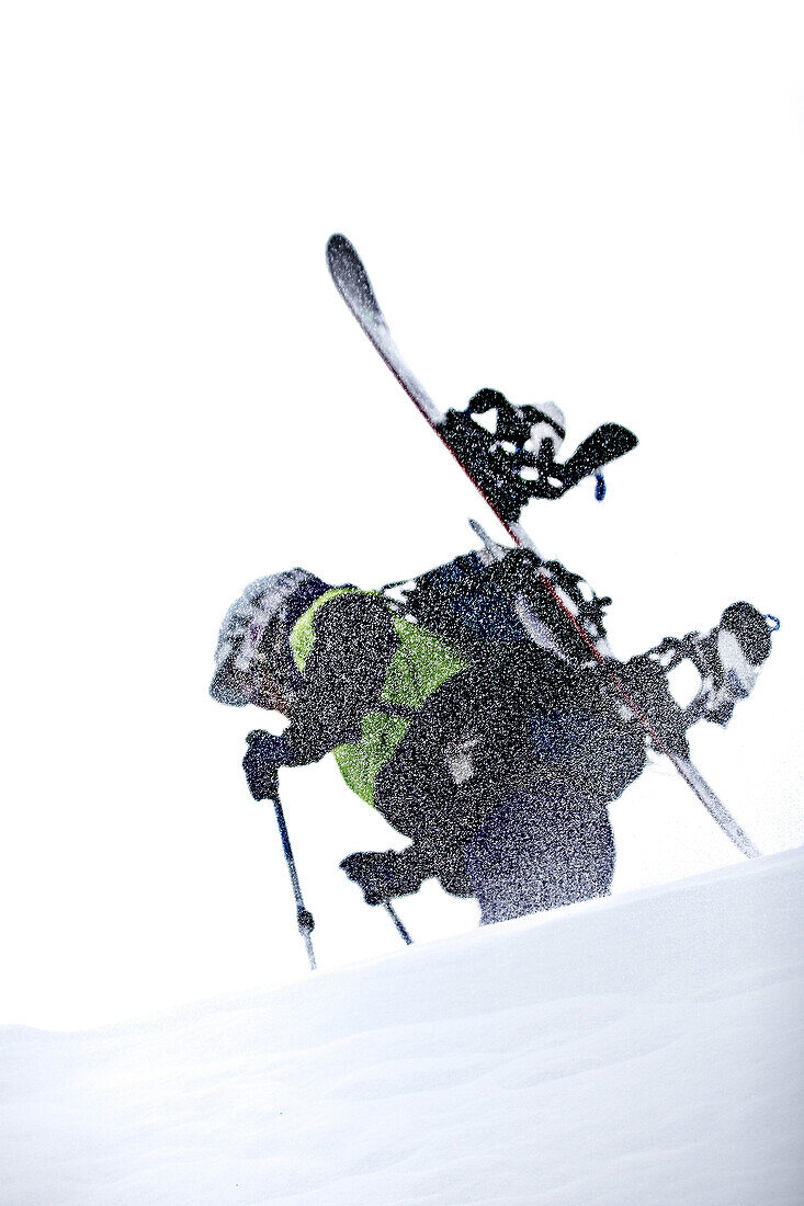 Young snowboarder hiking through the snow in the mountains while snowfall, Pitztal, Tyrol, Austria