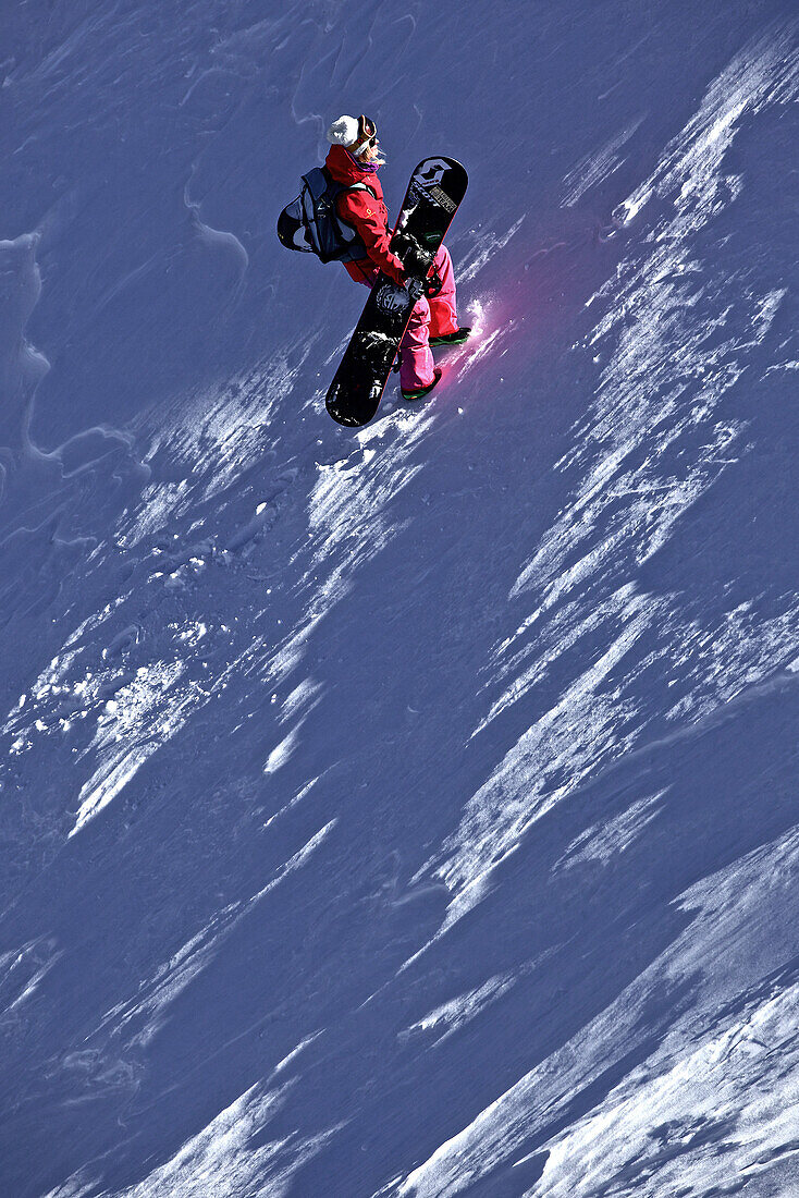 Female snowboarder hiking through deep powder snow in the mountains, Pitztal, Tyrol, Austria