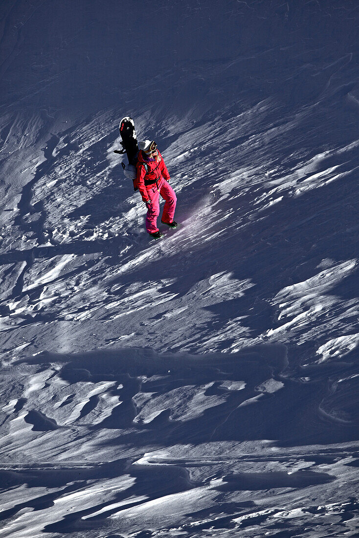 Female snowboarder hiking through deep powder snow in the mountains, Pitztal, Tyrol, Austria