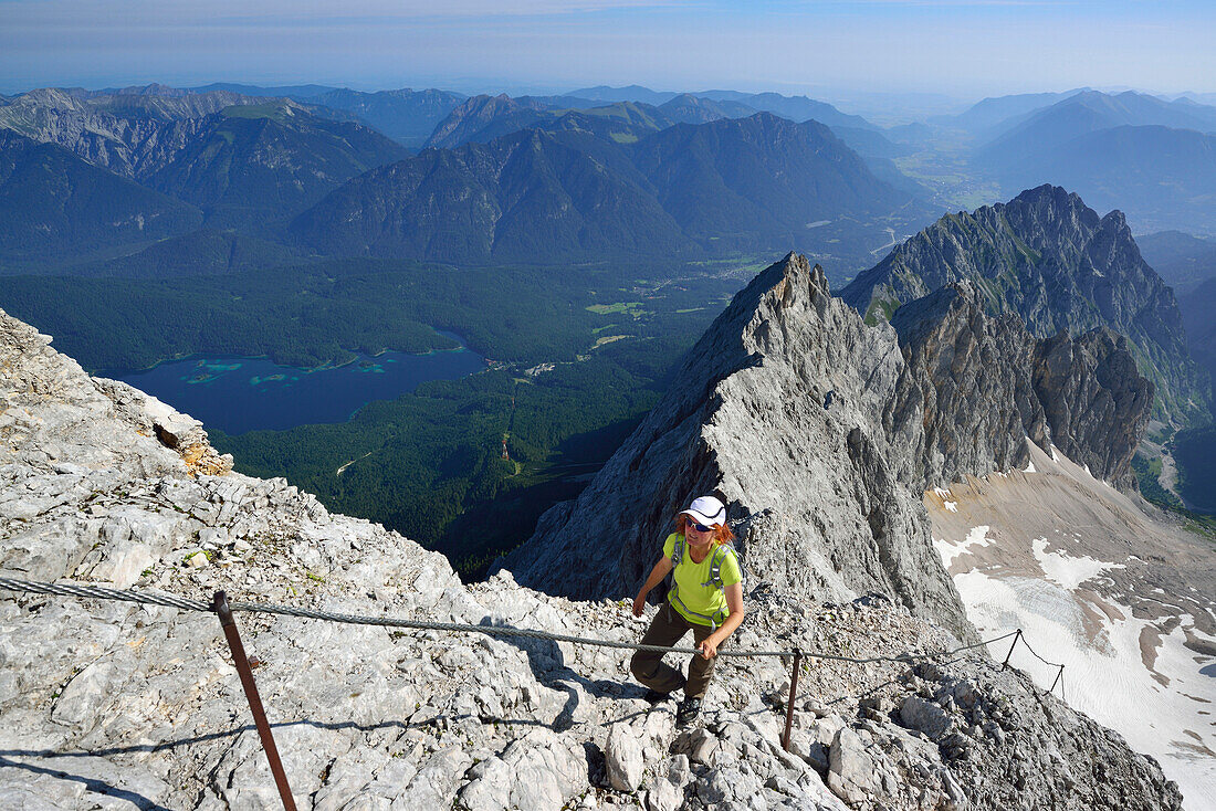 Woman ascending on fixed rope route to Zugspitze, lake Eibsee in background, Wetterstein mountain range, Upper Bavaria, Bavaria, Germany
