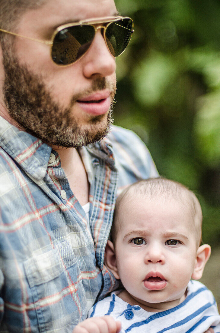 Man with Aviator Sunglasses and Beard Holding Infant Son, Outdoor