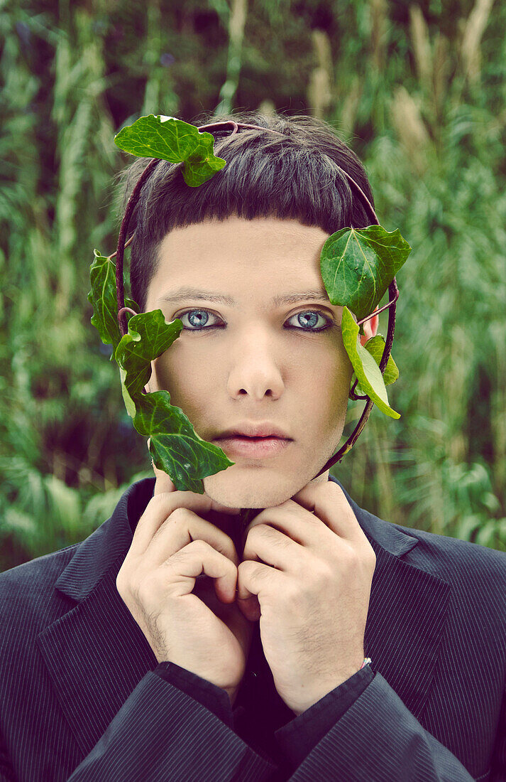 Young Man With Branch of Green Leaves Wrapped Around Face