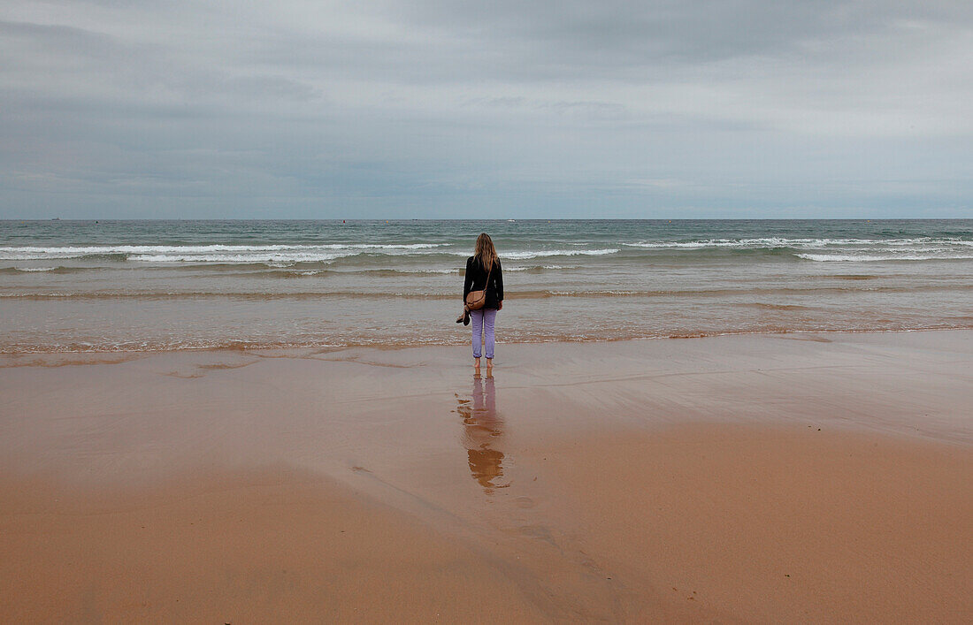 Young Woman on Beach Looking out to Sea, Rear View