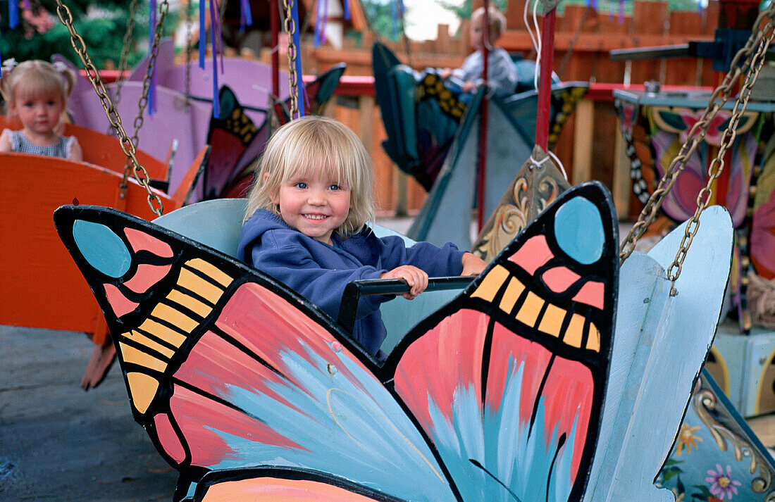 Young Blond Girl on Butterfly Ride at Amusement Park