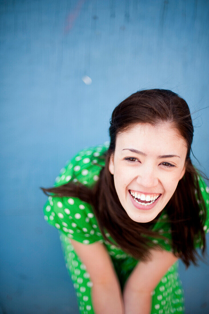 Lachende junge Frau in grünem Kleid mit Tupfen, hoher Blickwinkel
